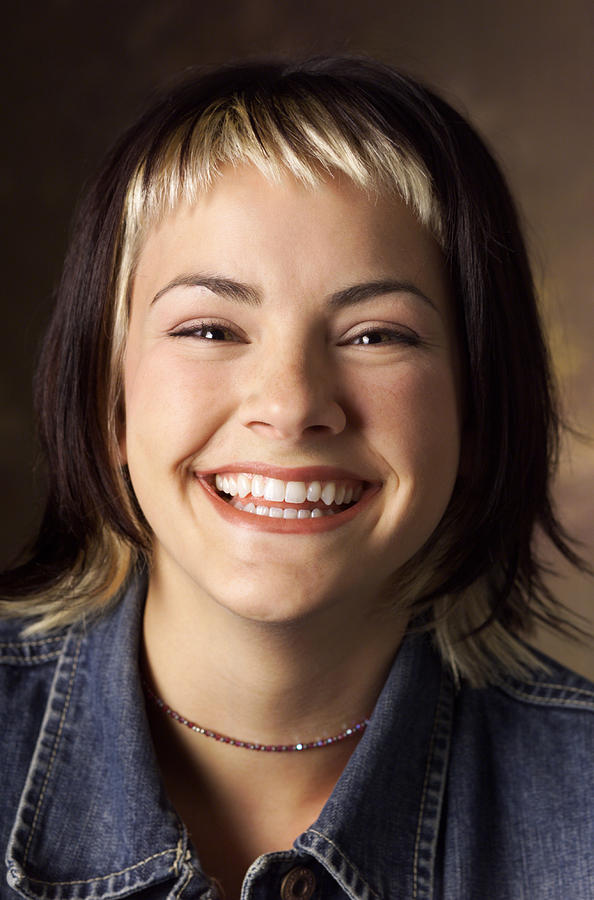 A Caucasian Young Woman With Brown And Blond Streaked Hair Wearing A Jean Jacket Is Smiling Joyfully Photograph by Photodisc