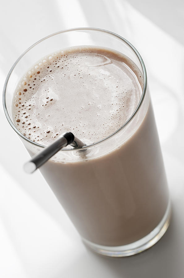 A chocolate milk in a clear glass with a straw Photograph by NightAndDayImages