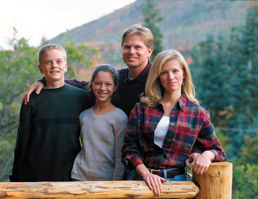 A Family Of Four Stands Together On A Cabin Porch Photograph by Photodisc