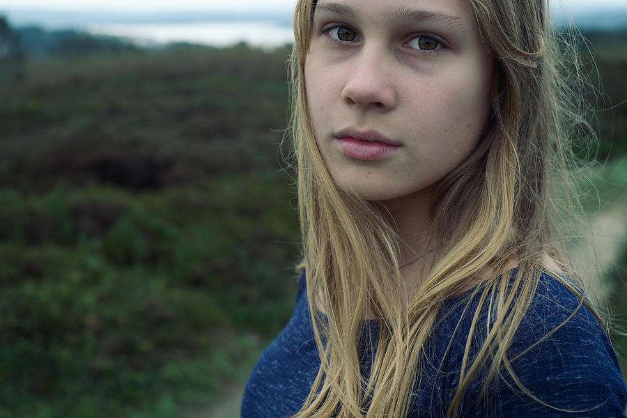 A girl looks at the camera on a background of a green meadow Photograph by Aleksandr Morozov