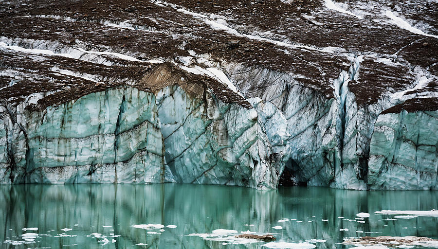 A Gravelly Glacier Cliff Reflected In A Photograph by Joel Koop / Design Pics