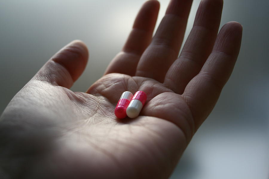 A Hand Holding Two Pills Photograph by Red Sky