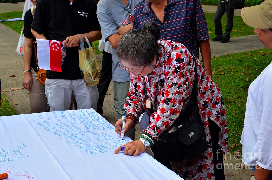 A lady signs petition at May Day rally Singapore Photograph by Imran Ahmed