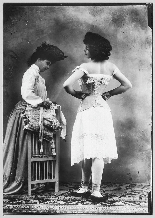 A Lady Tries On A Corset, While Photograph by Mary Evans Picture ...