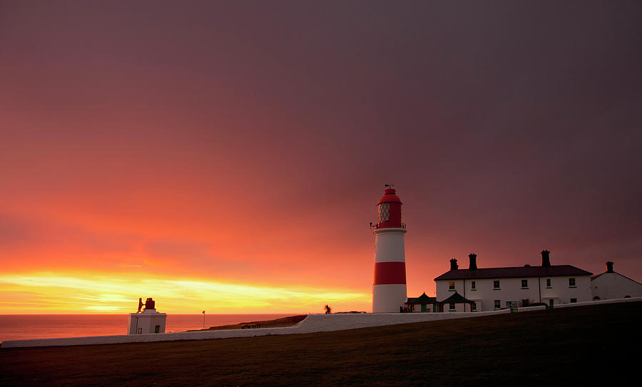 A Lighthouse On The Coast At Sunset Photograph by John Short