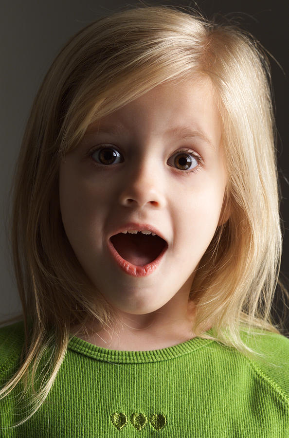 A Little Blond Girl In A Green Shirt Stares Wide Eyed And Open Mouthed With An Expression Of Surprise Photograph by Photodisc
