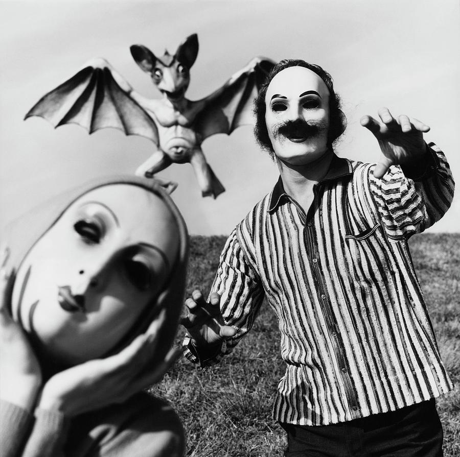 A Man And Woman Wearing Masks With A Bat Flying Photograph by Chadwick Hall A Man And Woman Wearing Masks With A Bat Flying Photograph by Chadwick Hall