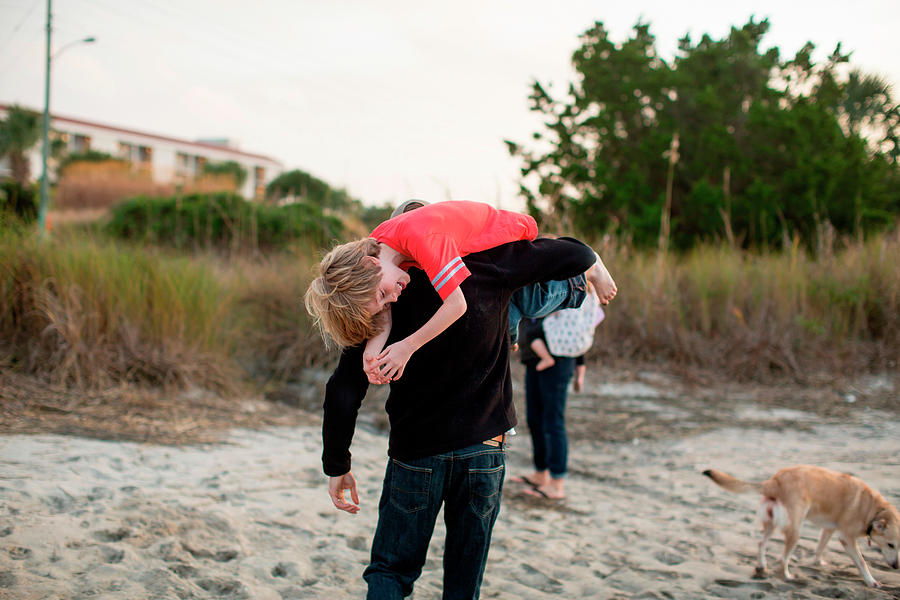 Sunset Photograph - A Man Carries His Son Over His Shoulder by Logan Mock-Bunting