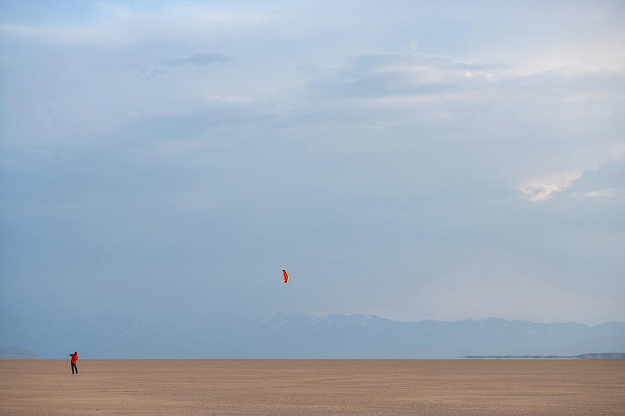 Nature Photograph - A Man Flying A Kite In An Open Desert by Wood Wheatcroft