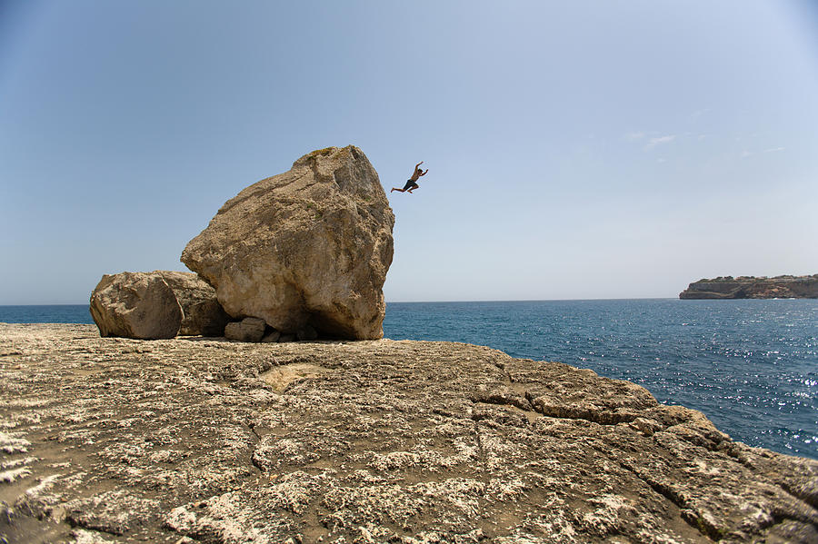 Action Photograph - A Man Jumping Off Of A Boulder by Corey Rich