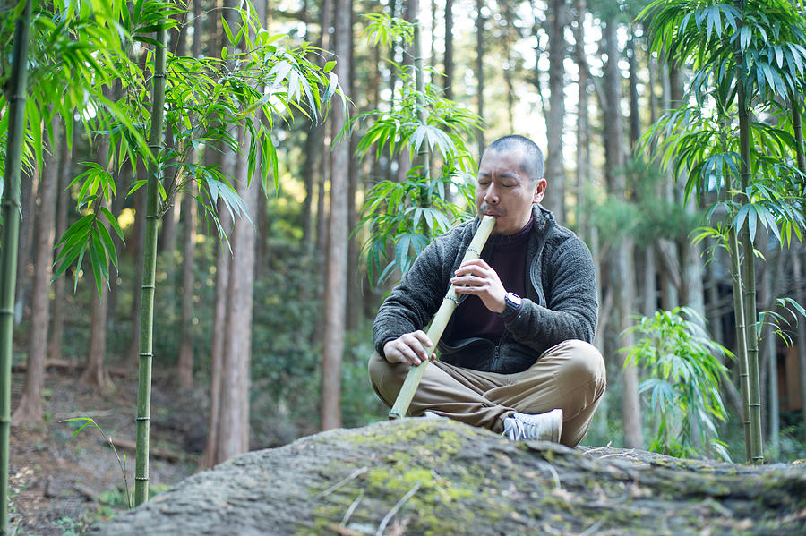 A man playing bamboo flute in the bamboo forest Photograph by Toshiro Shimada