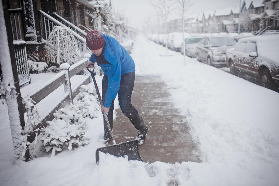A man shovels the sidewalk outside of his suburban house. Photograph by Christopher Kimmel
