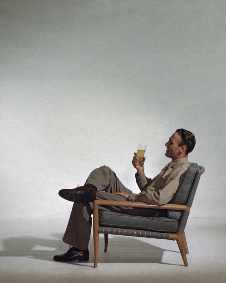 A Man Sitting In An Armchair With A Drink Photograph by John Rawlings