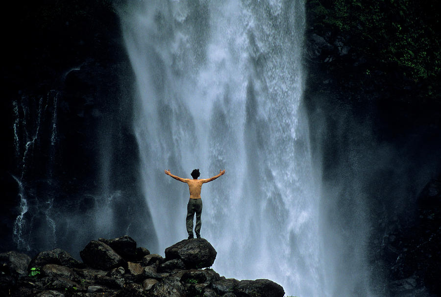 Waterfall Photograph - A Man Stands Beneath The A Waterfall by Celin Serbo