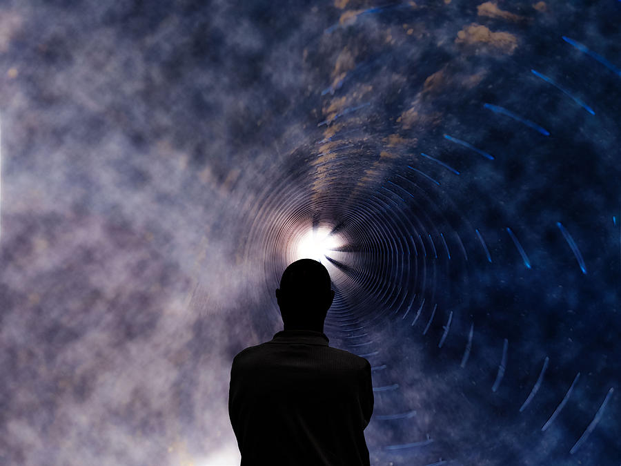 A man stands in a tunnel with light at the end. Photograph by Iryna Dobytchina