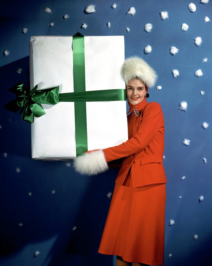 A Model Carrying A Large Wrapped Gift Photograph by John Rawlings