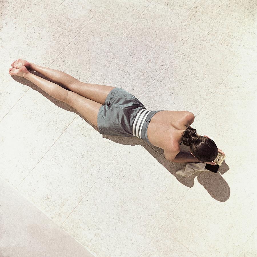 A Model Lying Down Wearing A Play Suit Photograph by John Rawlings