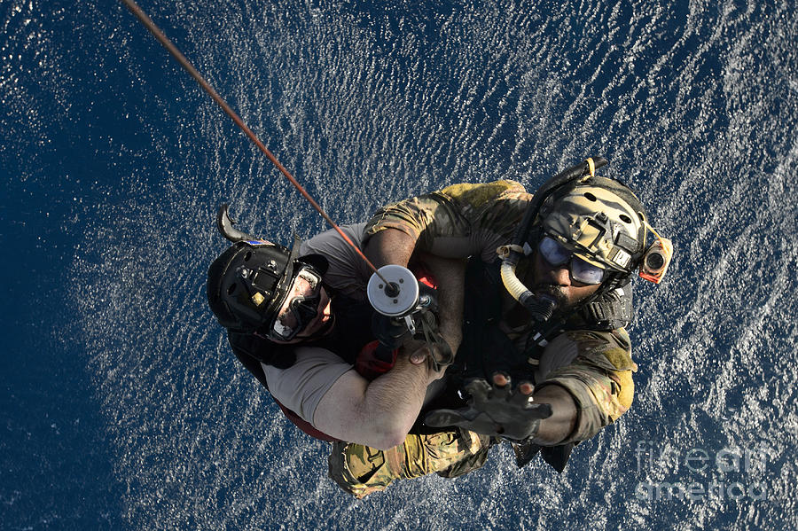A Pararescueman And Rescuee Are Hoisted Photograph