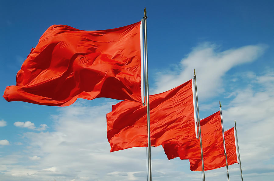 A row of red flags blowing in the wind Photograph by Mozcann