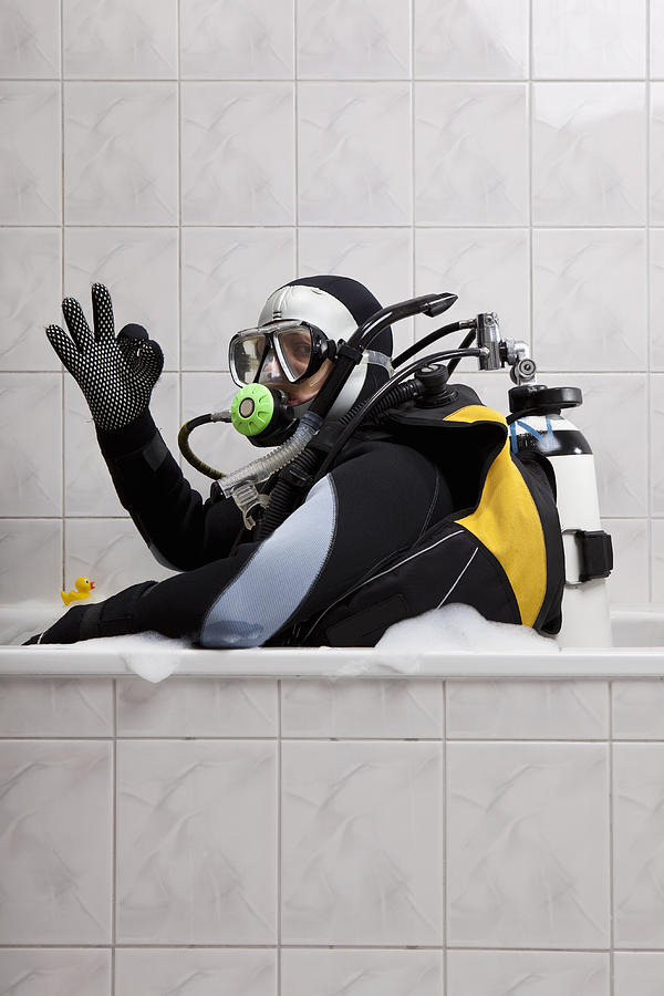 A scuba diver sitting in a bubble bath giving the OK sign Photograph by fStop Images - Twins