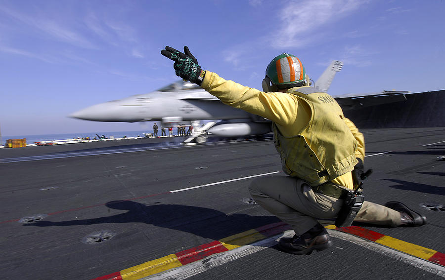A shooter signals the launch of an F/A-18 Super Hornet. Photograph by Stocktrek Images