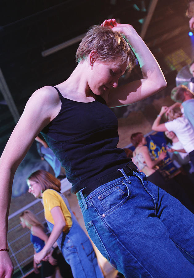 A Short Haired Blonde Woman In Blue Jeans And A Black Tank Top Is Dancing In A Nightclub Photograph by Photodisc