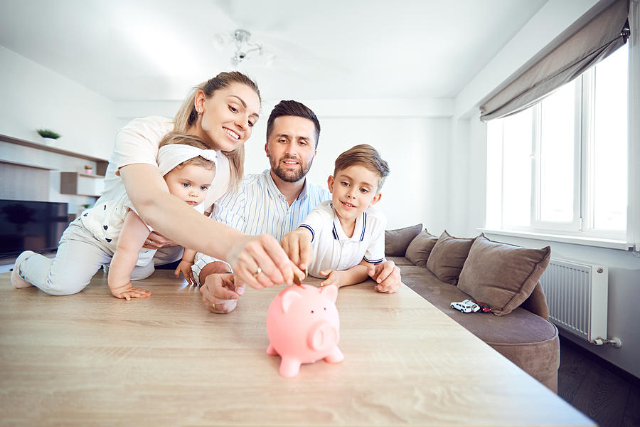 A smiling family saves money with a piggy bank Photograph by Lacheev