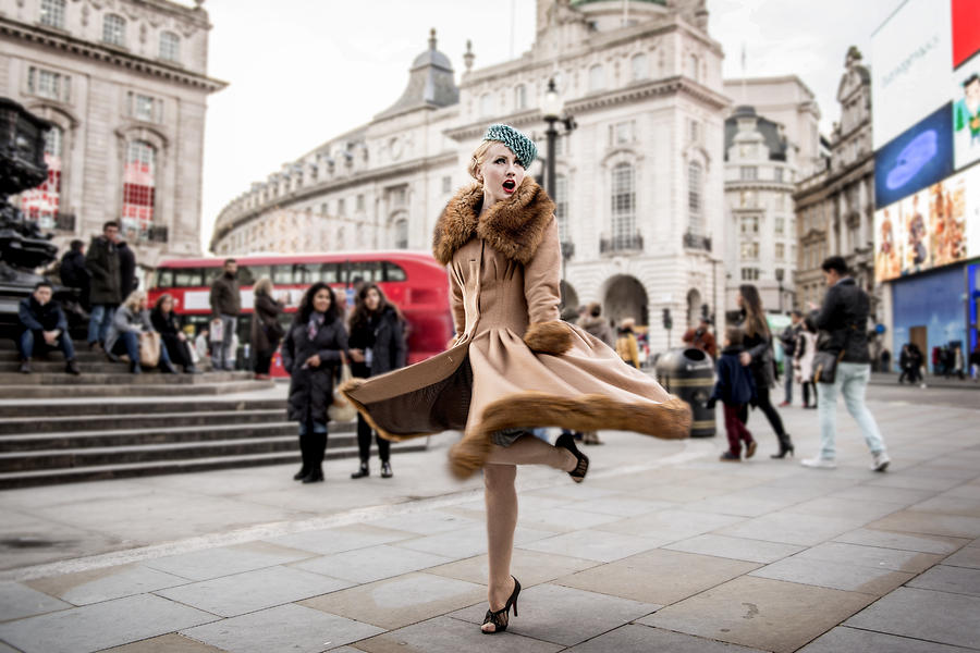 A stylish young woman dressed in 1930s style clothing twirling around by the statue of Eros at Piccadilly Circus Photograph by Loop Images RF