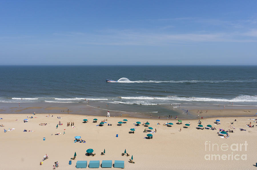 A touring speedboat passes by shore in Ocean City Maryland Photograph by William Kuta