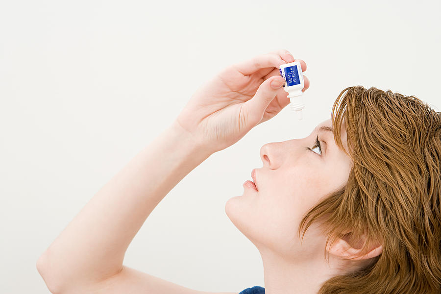 A woman applying eye drops Photograph by Image Source