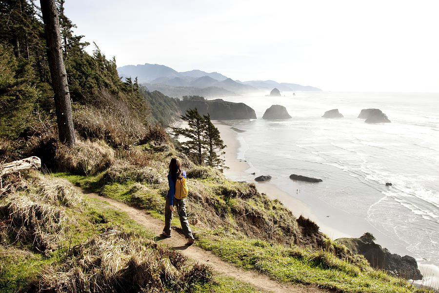 A woman hiking a secluded path along the coastline. Photograph by Jordan Siemens