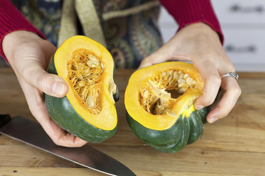 A woman holding two halves of acorn squash Photograph by Sims, Amy Kalyn