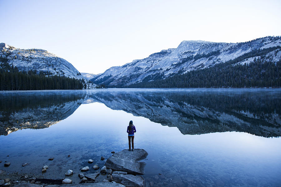 A woman watching the sunrise over a lake. Photograph by Jordan Siemens