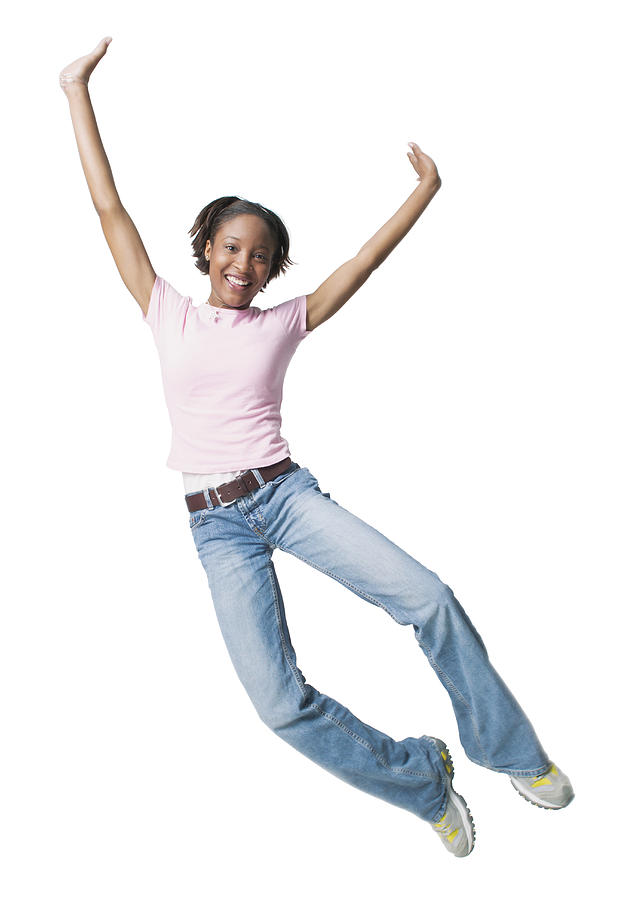 A Young African American Woman In Jeans And A Pink Shirt Jumps Up Playfully Through The Air Photograph by Photodisc