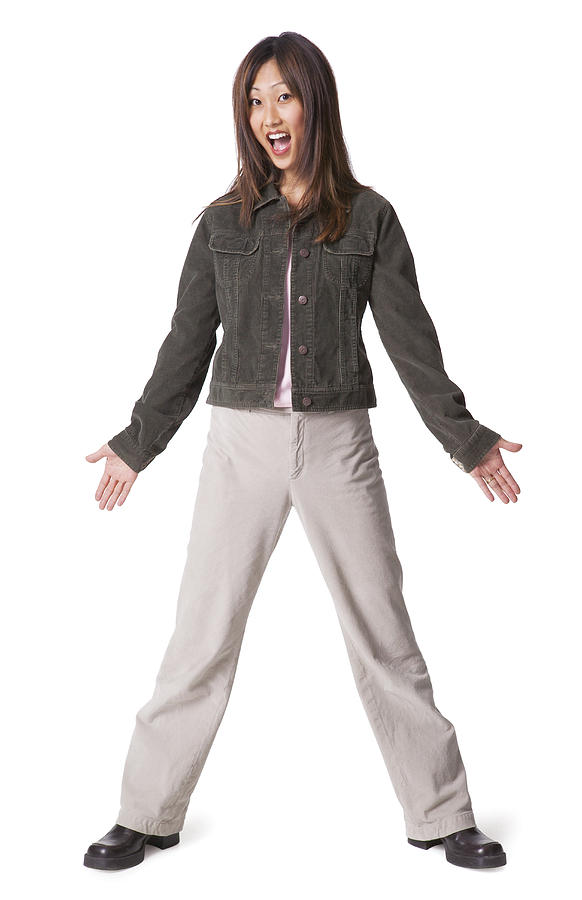 A Young Asian Woman Dressed In Tan Pants And A Jean Jacket Spreads Out Her Arms And Flashes A Surprised Expression Photograph by Photodisc