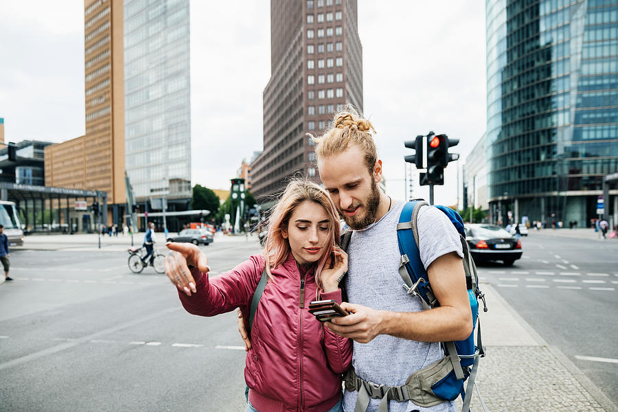 A Young Backpacking Couple Standing On Corner Of Busy City Street Photograph by Hinterhaus Productions