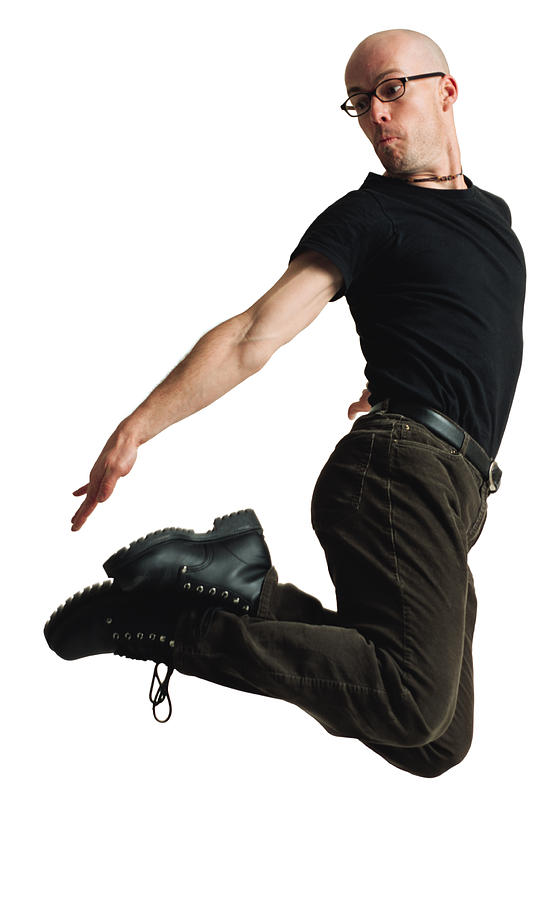 A Young Caucasian Bald Male Modern Dancer Dressed In Black And Wearing Glasses Jumps Up Twists His Body And Reaches For His Feet Photograph by Photodisc