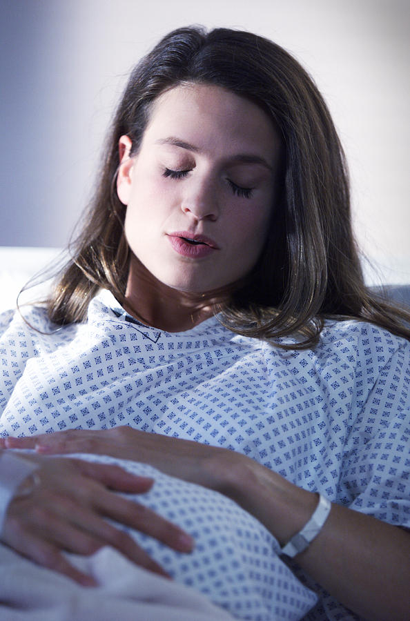 A Young Caucasian Expectant Mother Lays In A Hospital Bed As She  Experiences A Contraction Photograph by Photodisc