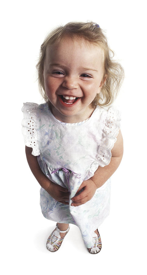 A Young Female Child In A White Printed Dress Laughs And Smiles Up To The Camera Photograph by Photodisc