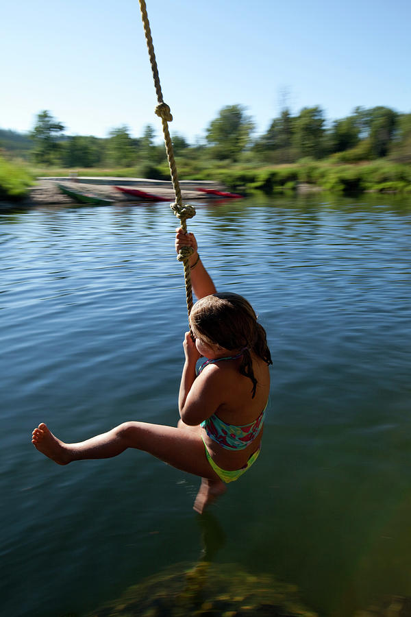 A Young Girl Hanging On To A Rope Swing