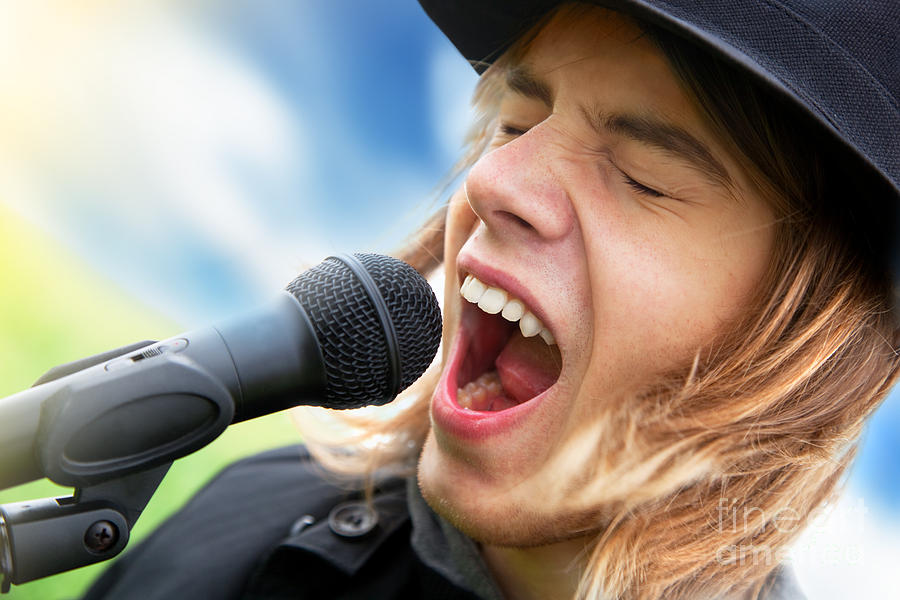 A young man sings to a microphone Photograph by Michal Bednarek