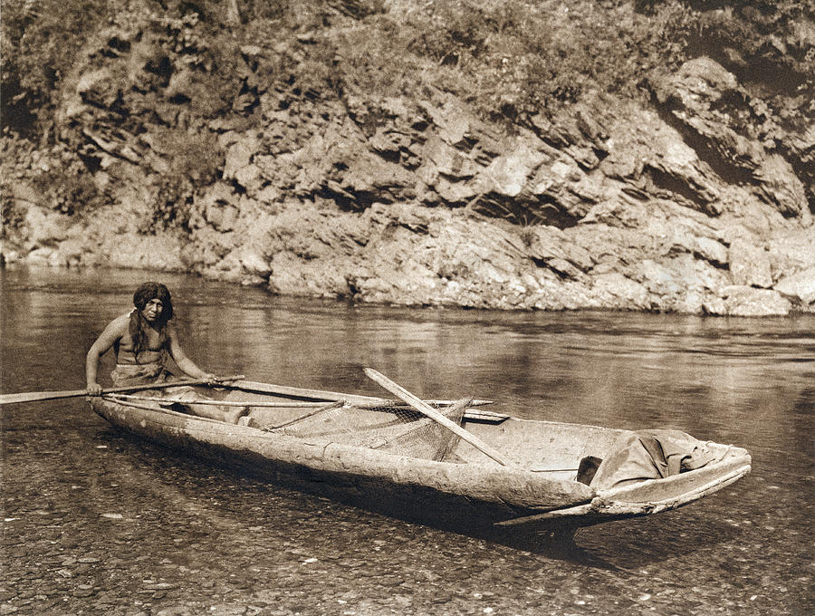 Black And White Photograph - A Yurok In His Dugout Canoe by Underwood Archives