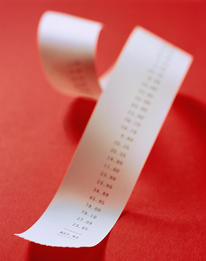 Adding machine receipt coiled on red background, part blurred effect Photograph by Nick Dolding