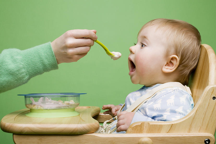 Adult feeding baby Photograph by Image Source