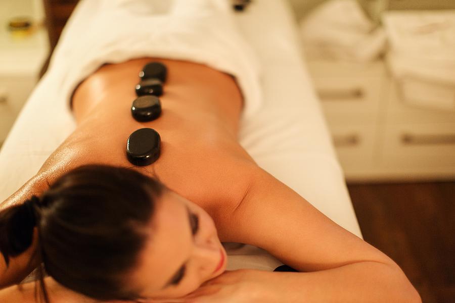 Adult woman having hot stone massage in spa salon Photograph by Milanvirijevic