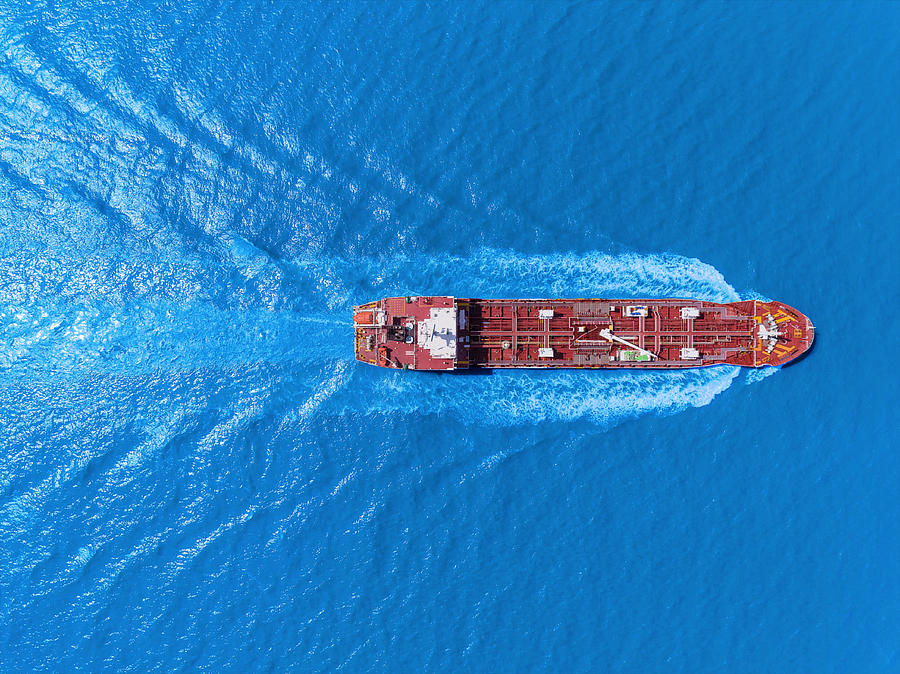 Aerial top view Oil ship tanker full speed with beautiful wave pattern transportation from refinery on the sea. Photograph by Suriyapong Thongsawang