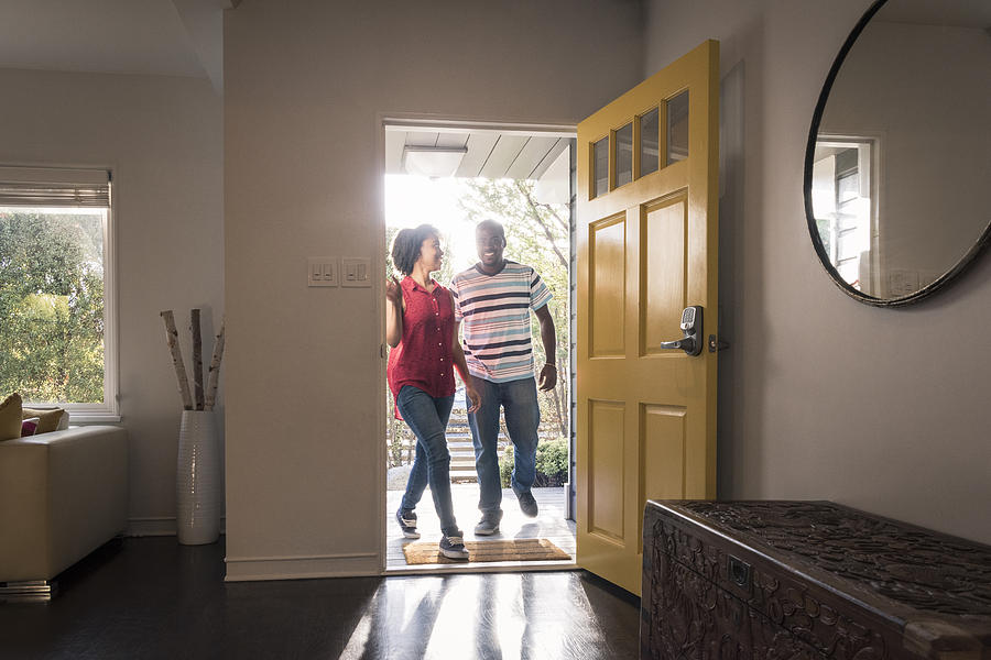 African American couple arriving home in doorway, smiling Photograph by Johnny Greig