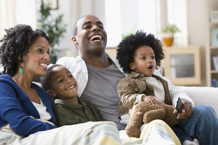 African American family watching television together Photograph by Jose Luis Pelaez Inc