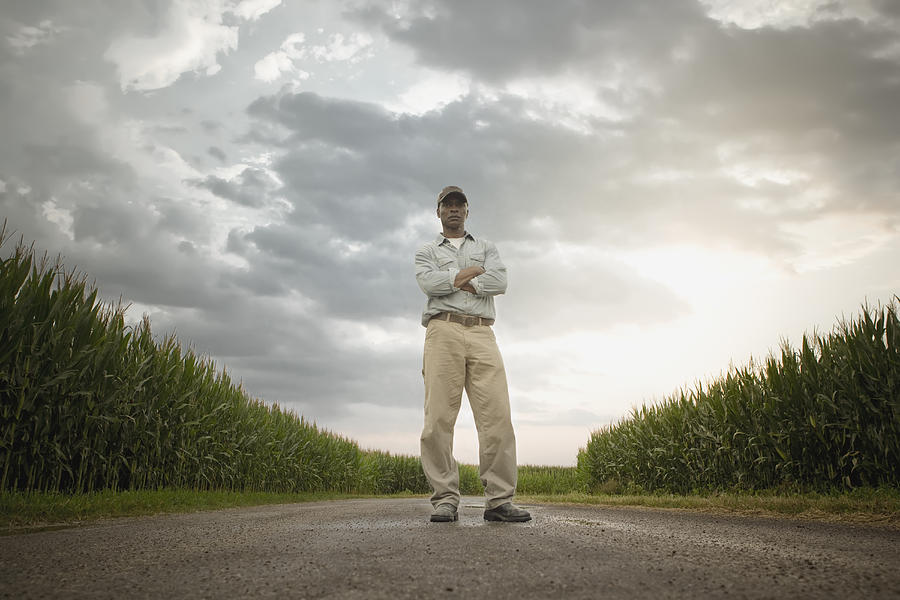 African American farmer standing on road through crops Photograph by John Fedele