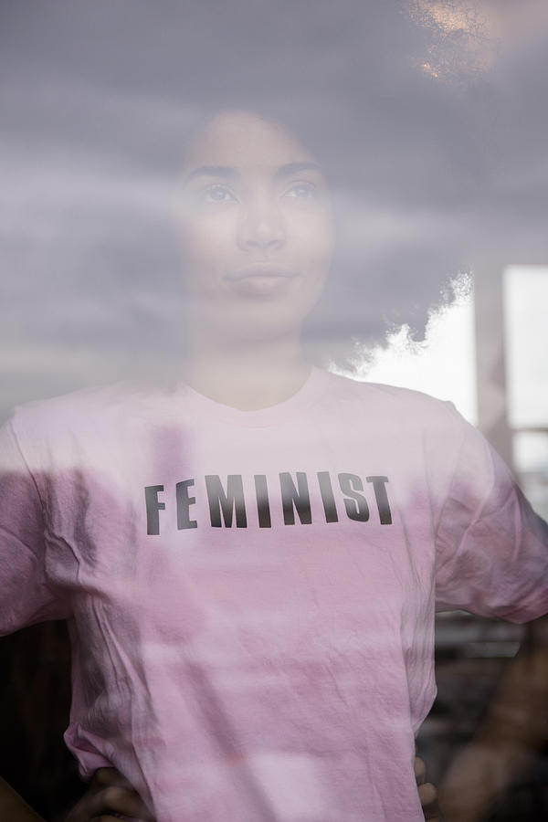 African American woman wearing feminist t-shirt behind window Photograph by JGI/Jamie Grill